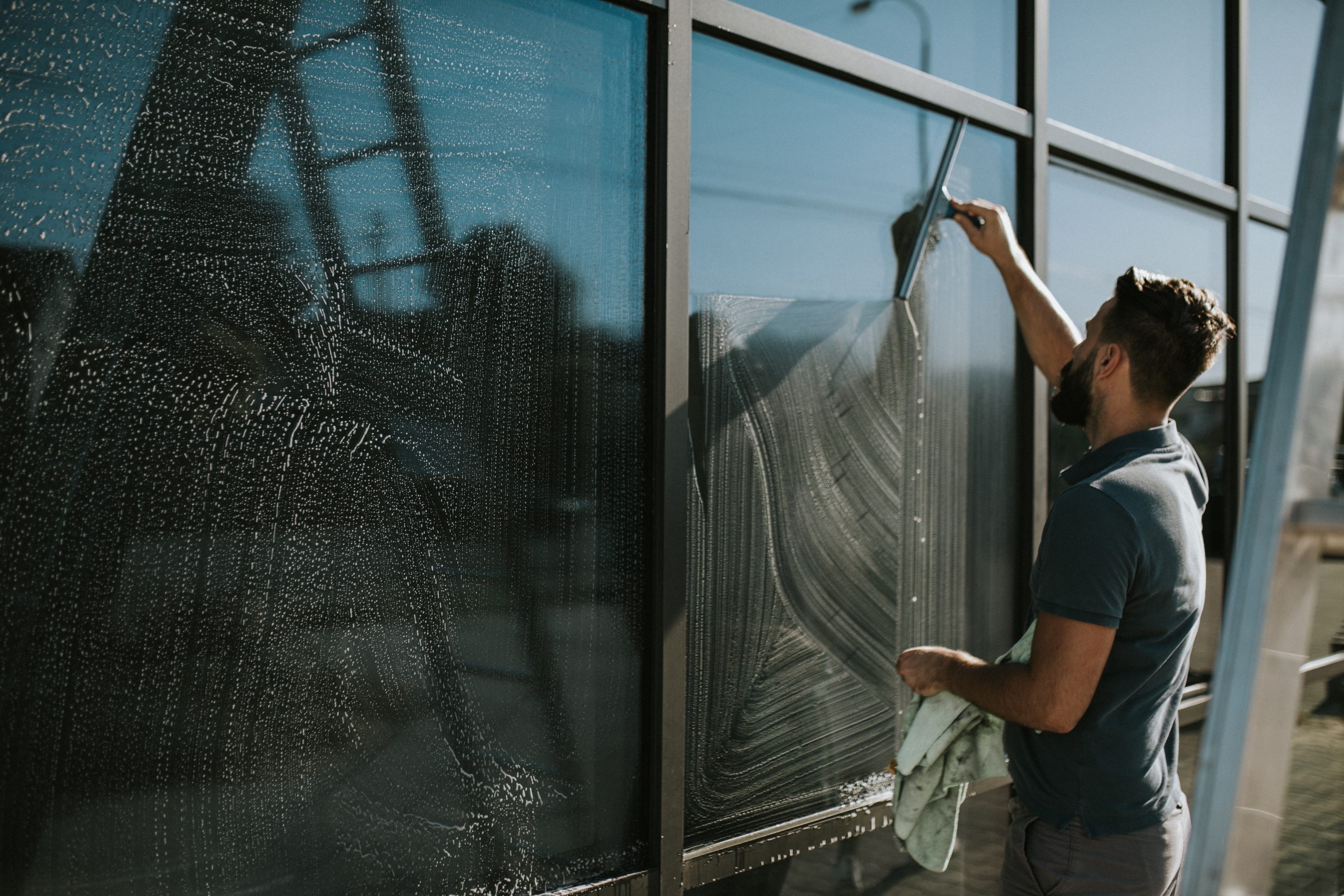 Mann reinigt eine Glasfassade